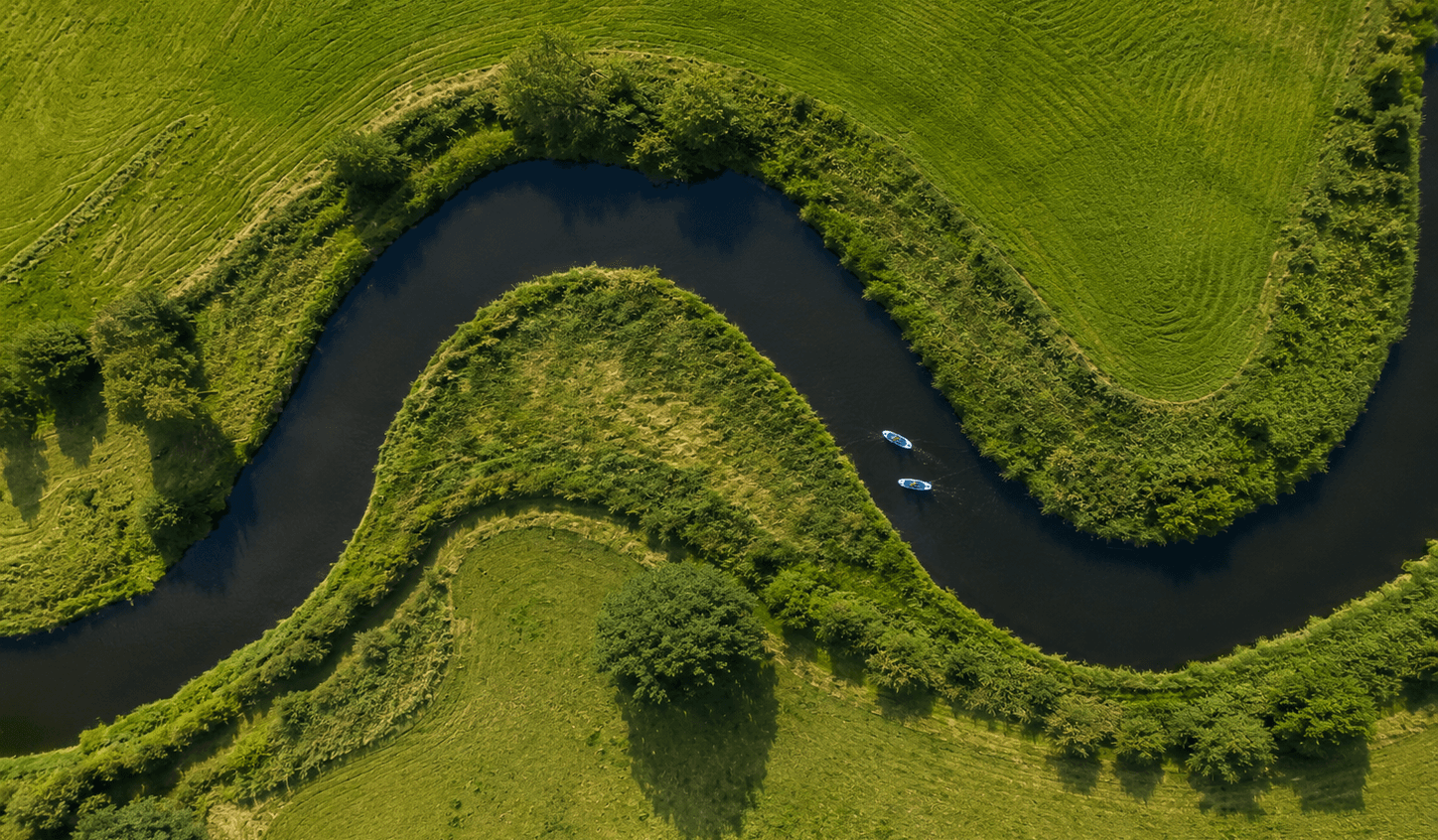 Aerial view of a winding river with paddleboarders